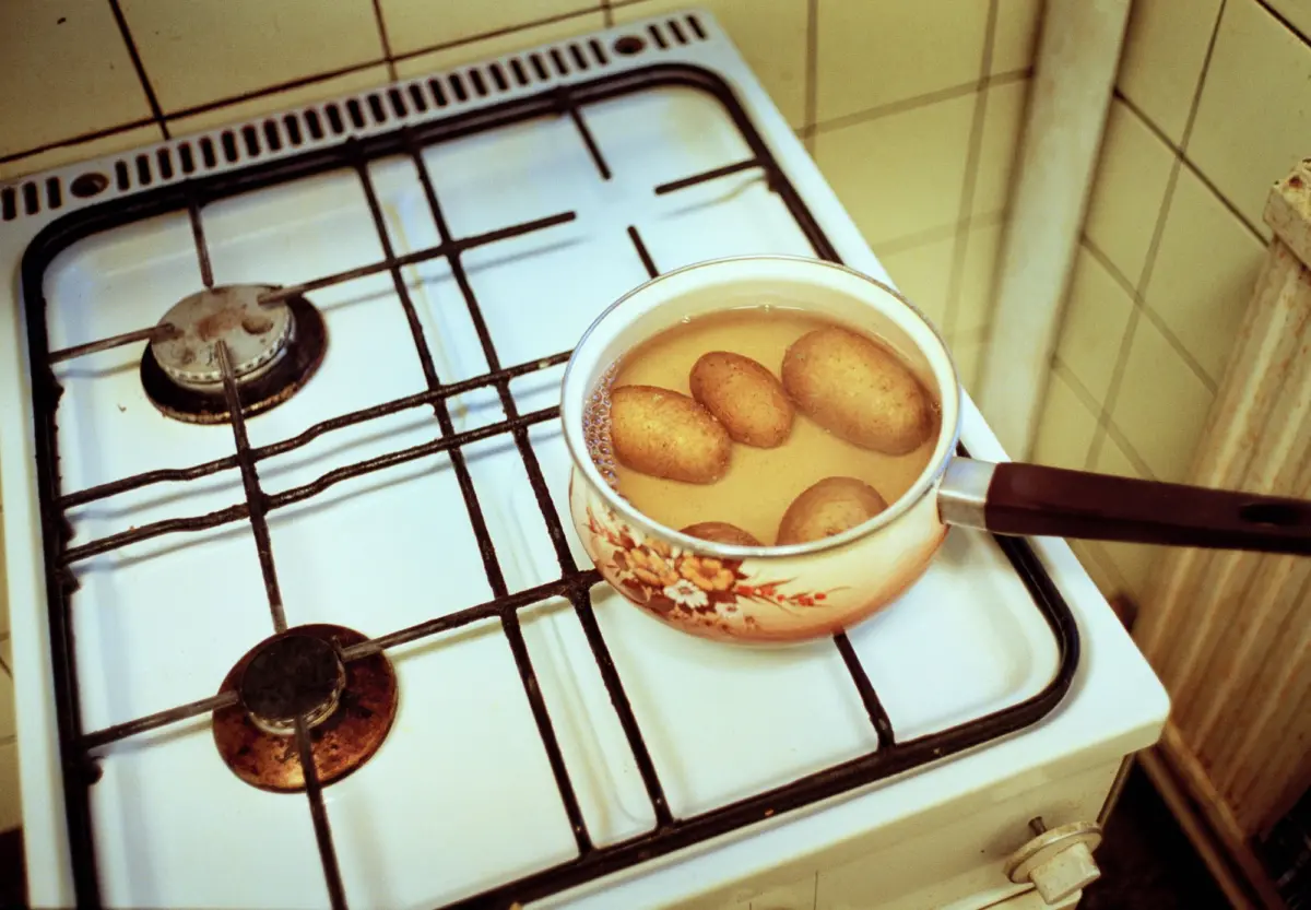 Enamel floral saucepan boiling eggs in water on a gas stove.