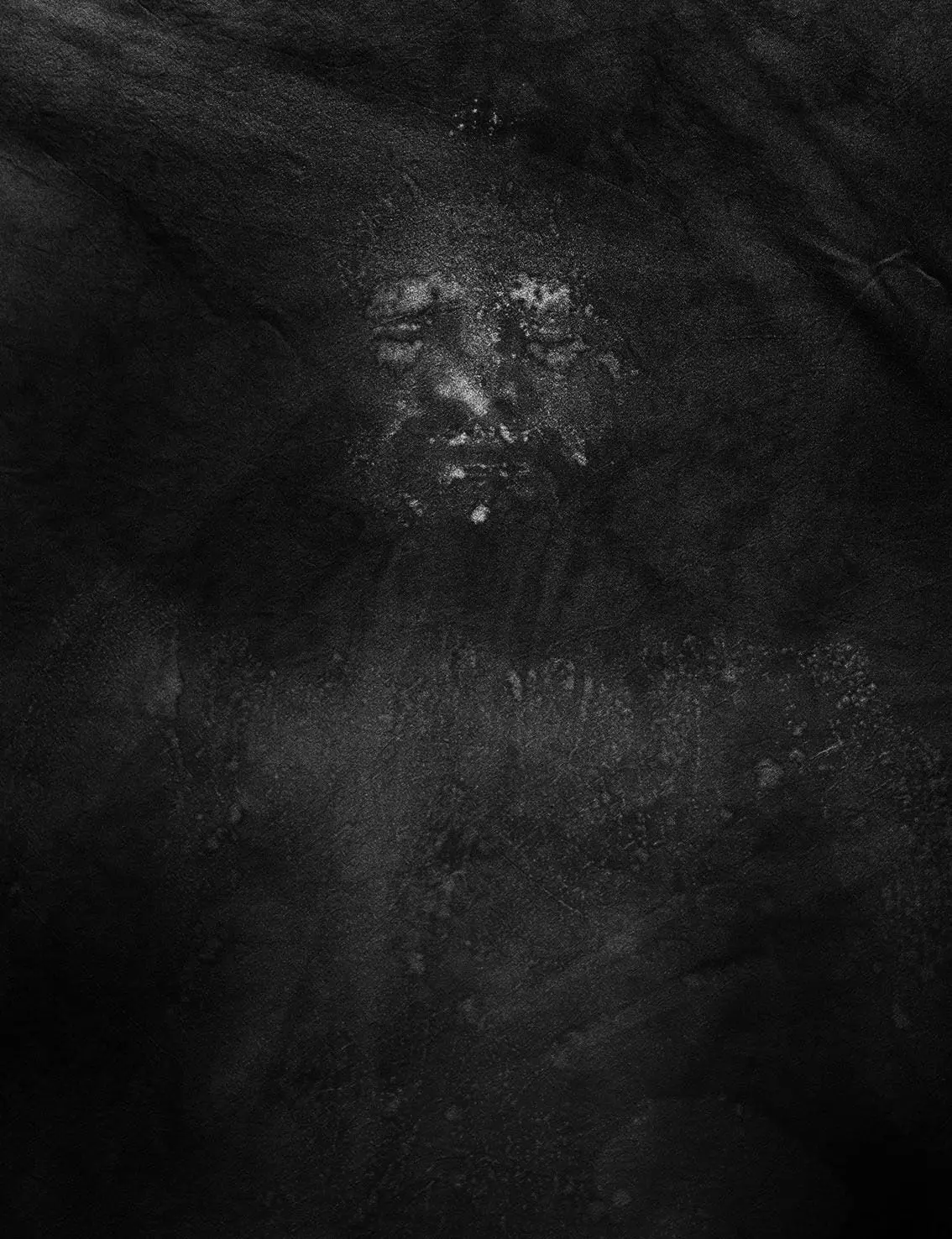 Faint face emerging from dark, textured surface.