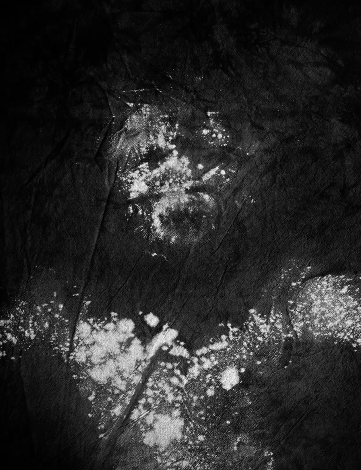 White powder splatters on a dark textured fabric surface.