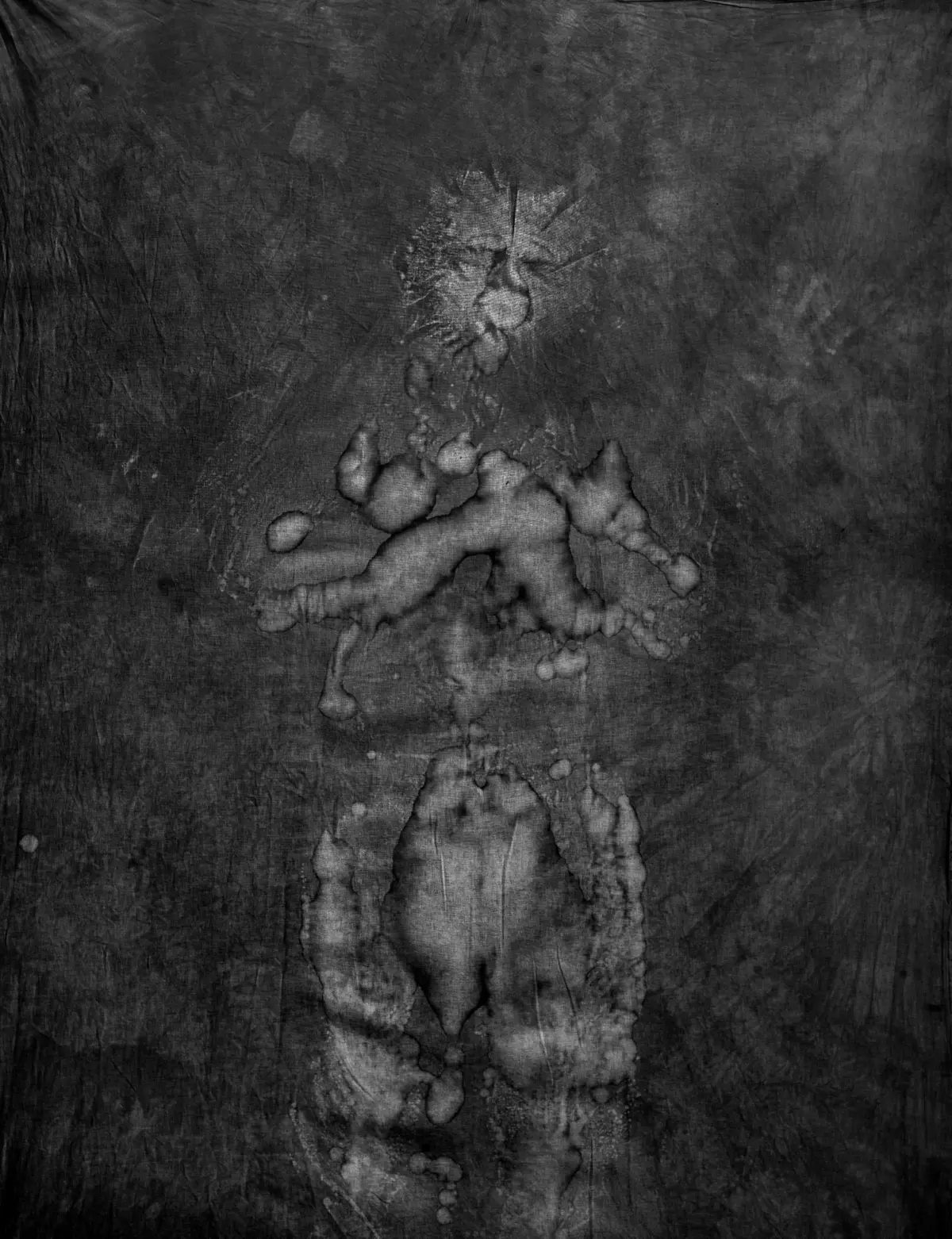 Abstract grayscale texture with a pale irregular stain forming a vertical band at the center of a dark, rough surface.