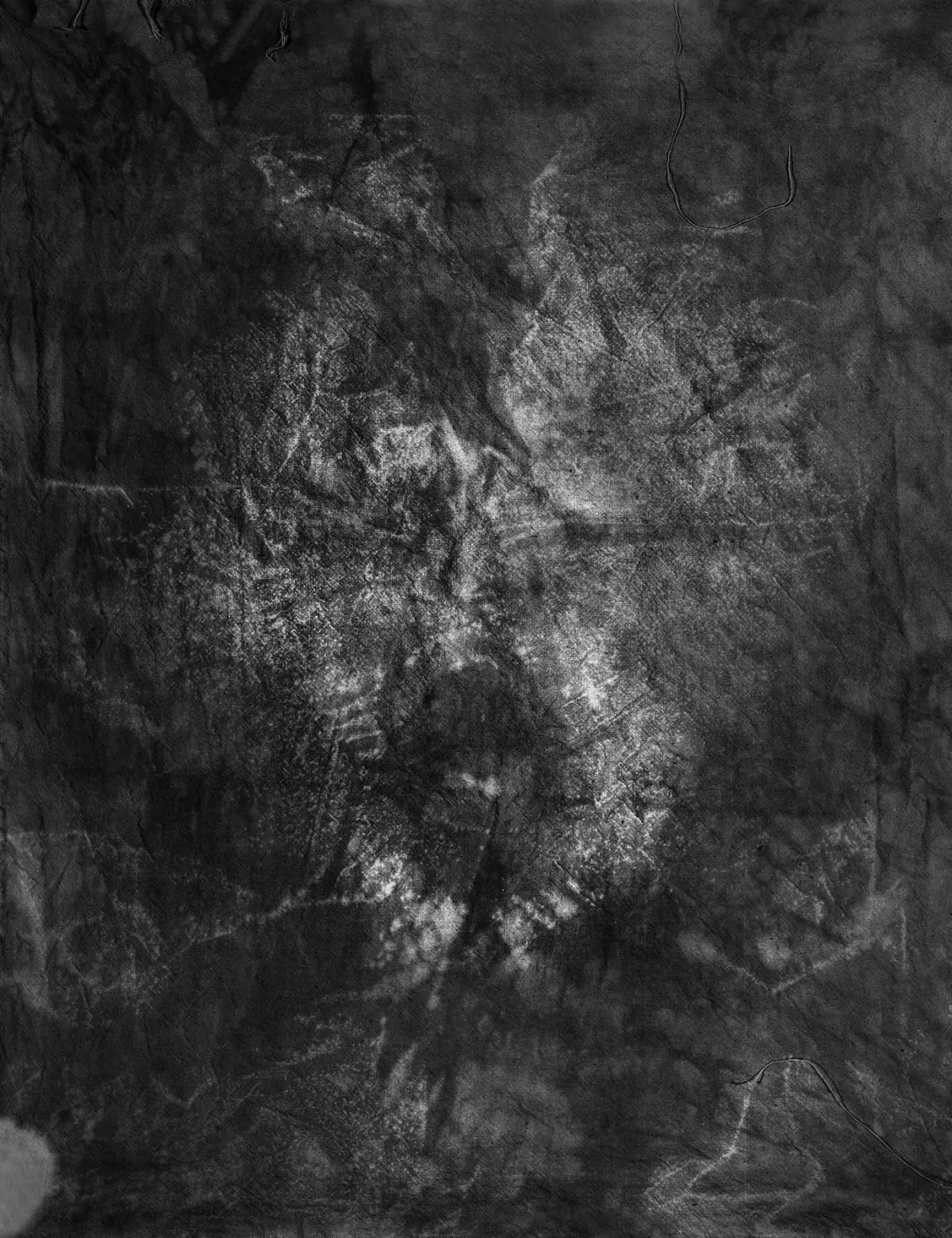 Close-up of wrinkled black fabric texture with light patches.