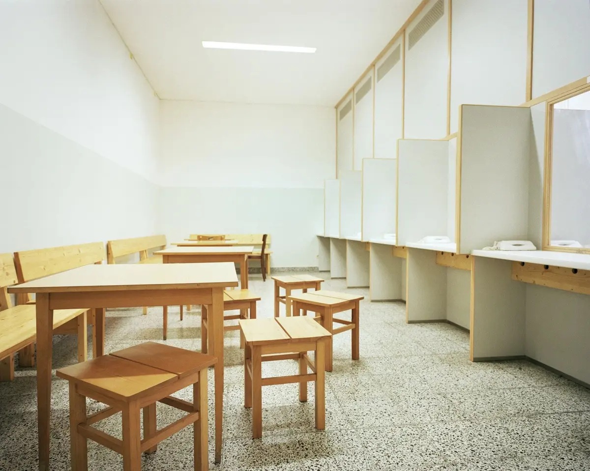 Empty study room with light wooden tables and stools; row of private cubicles with counters along the right wall.