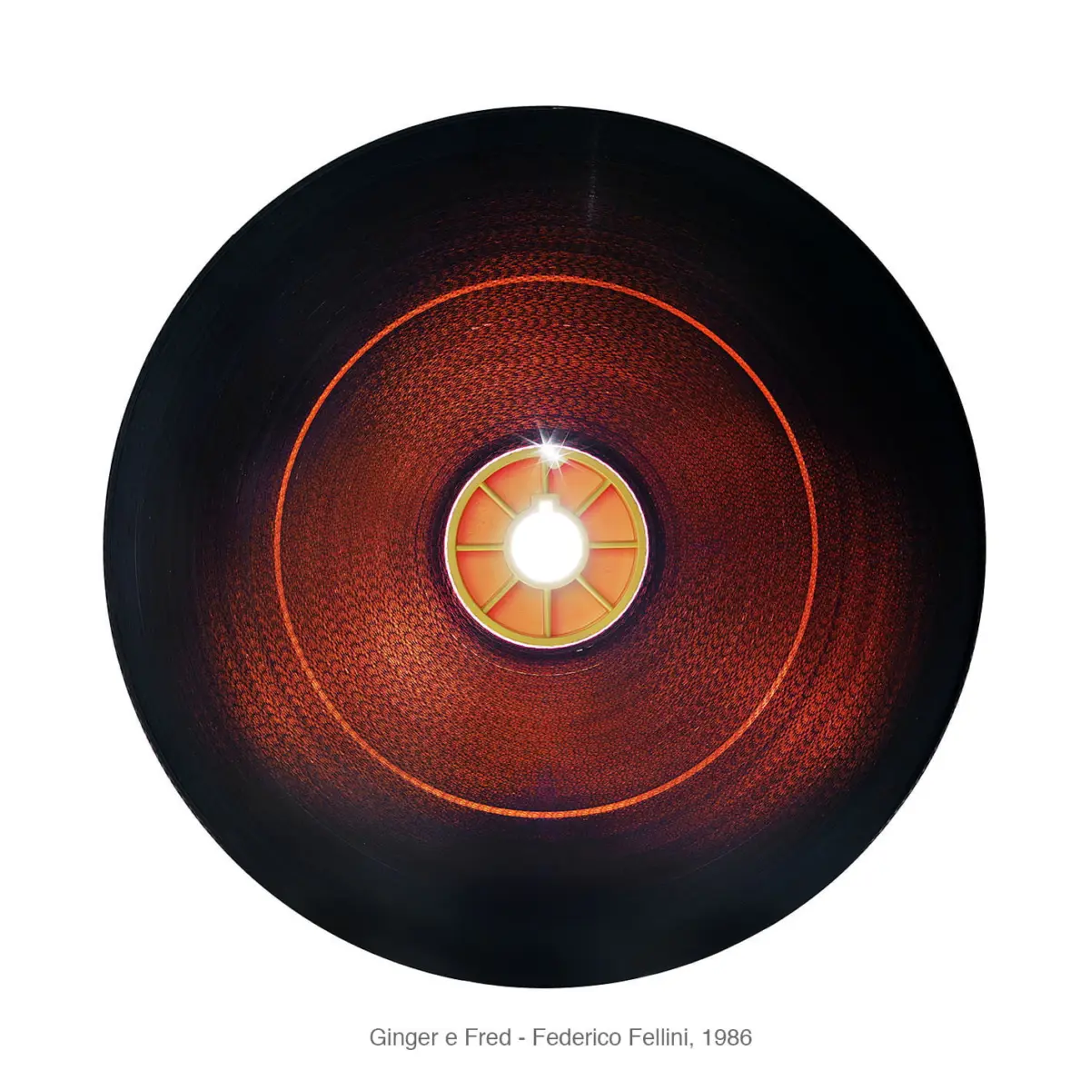 Close-up of a black vinyl record with a glowing orange-red center hub on a white background.