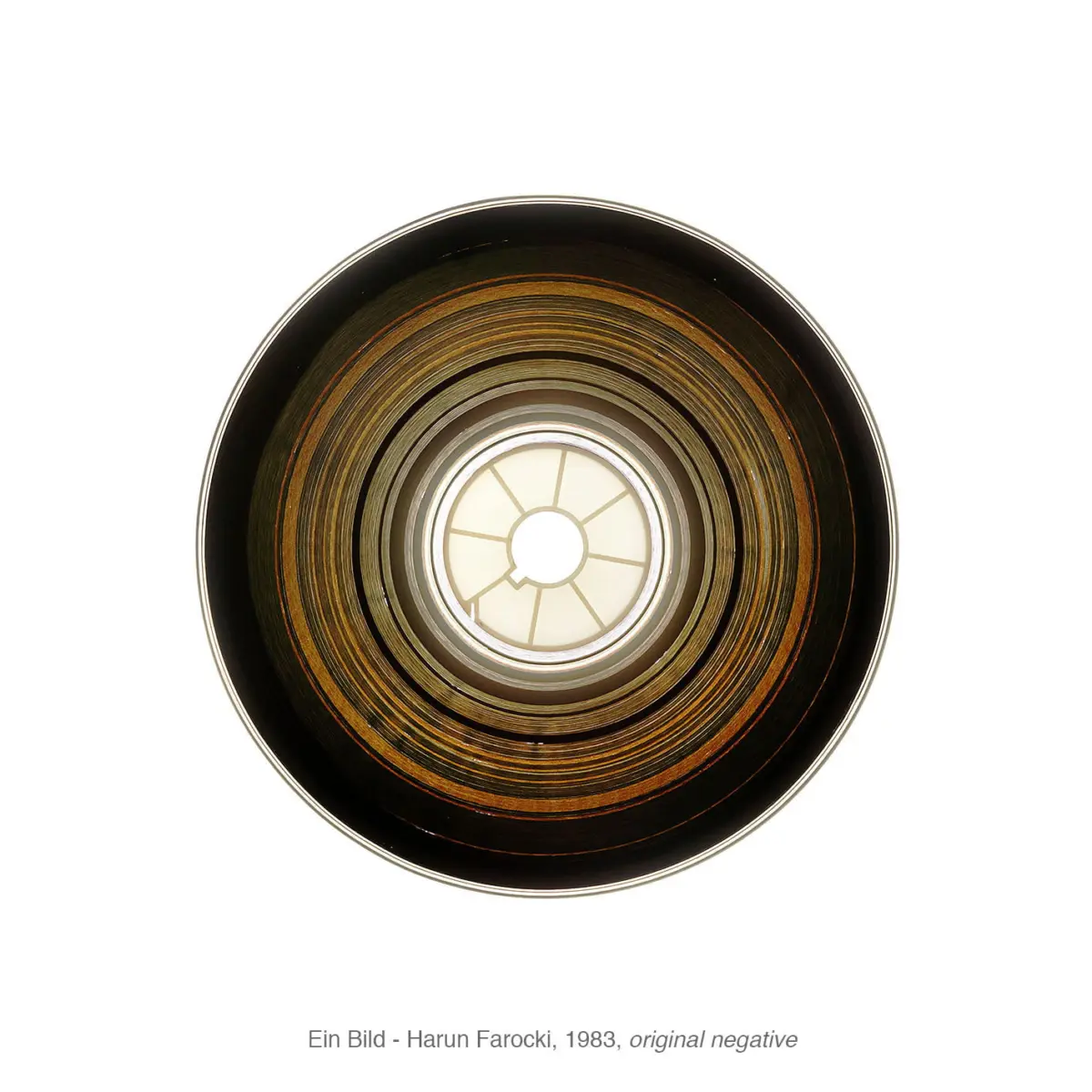 Overhead close-up of a circular, multi-layered metal disc with concentric rings and a pale segmented center.