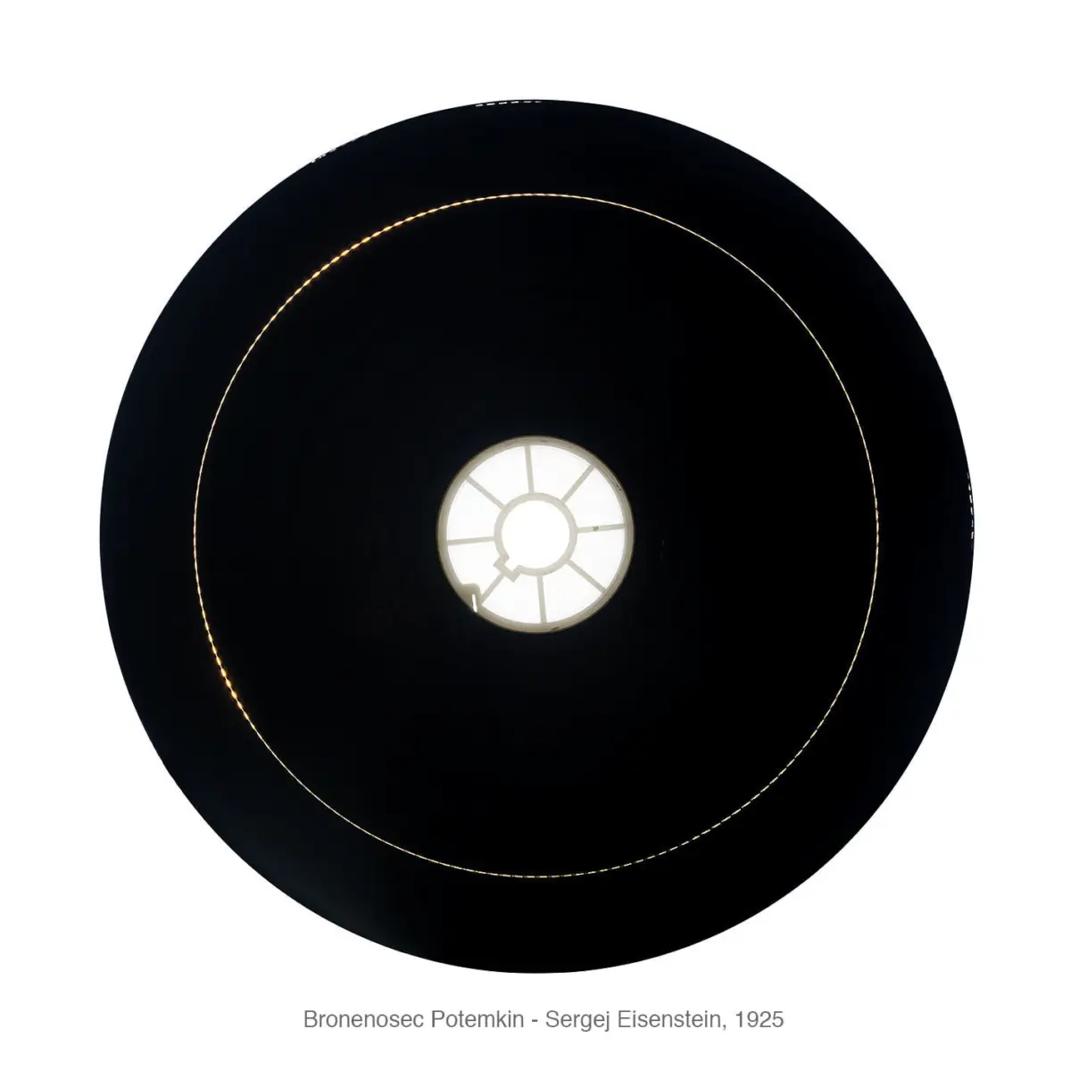 Looking up at a large black circular ceiling lamp with a glowing inner ring and a white circular central panel divided by radial spokes.