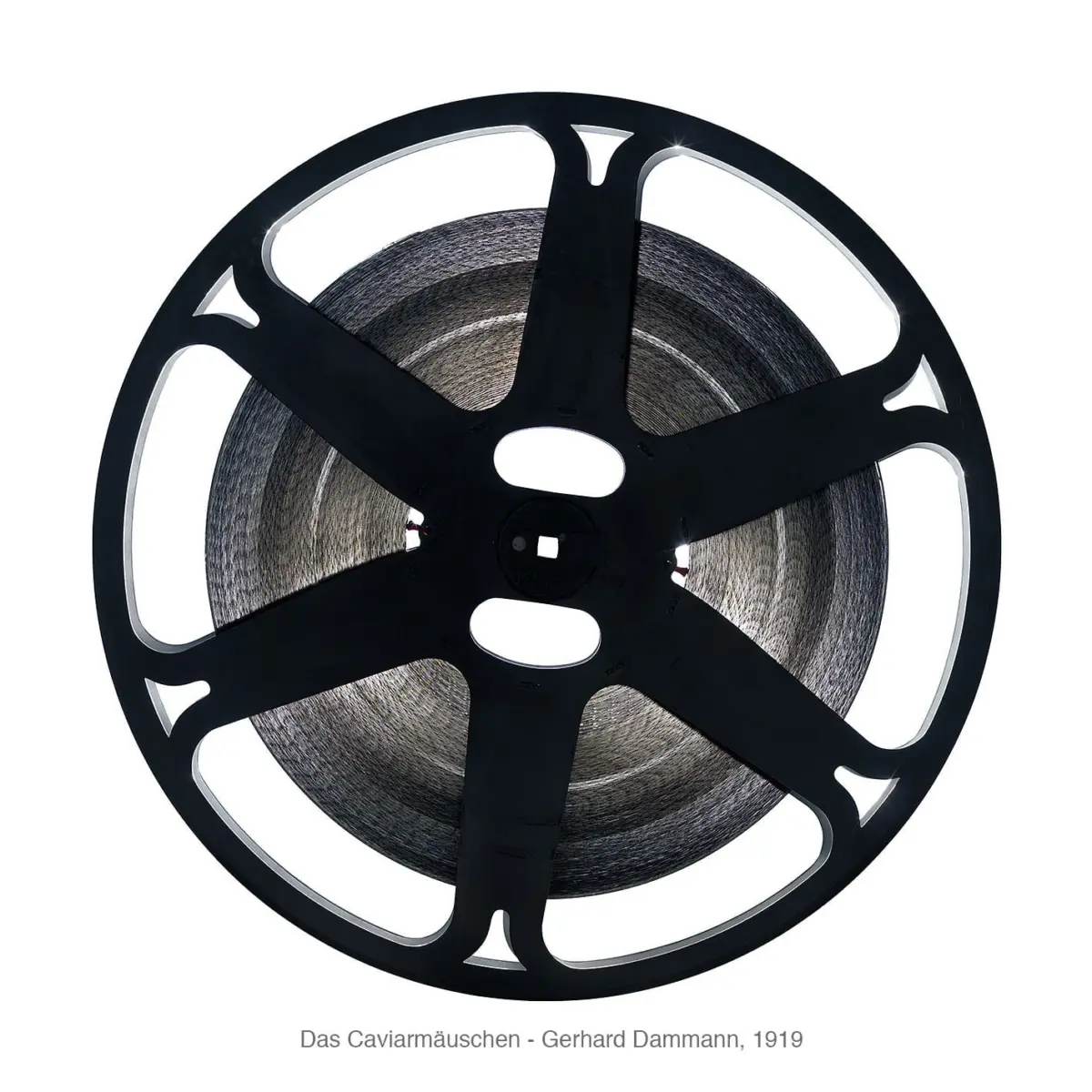 Close-up of a black film reel with tightly wound photographic film on a white background.