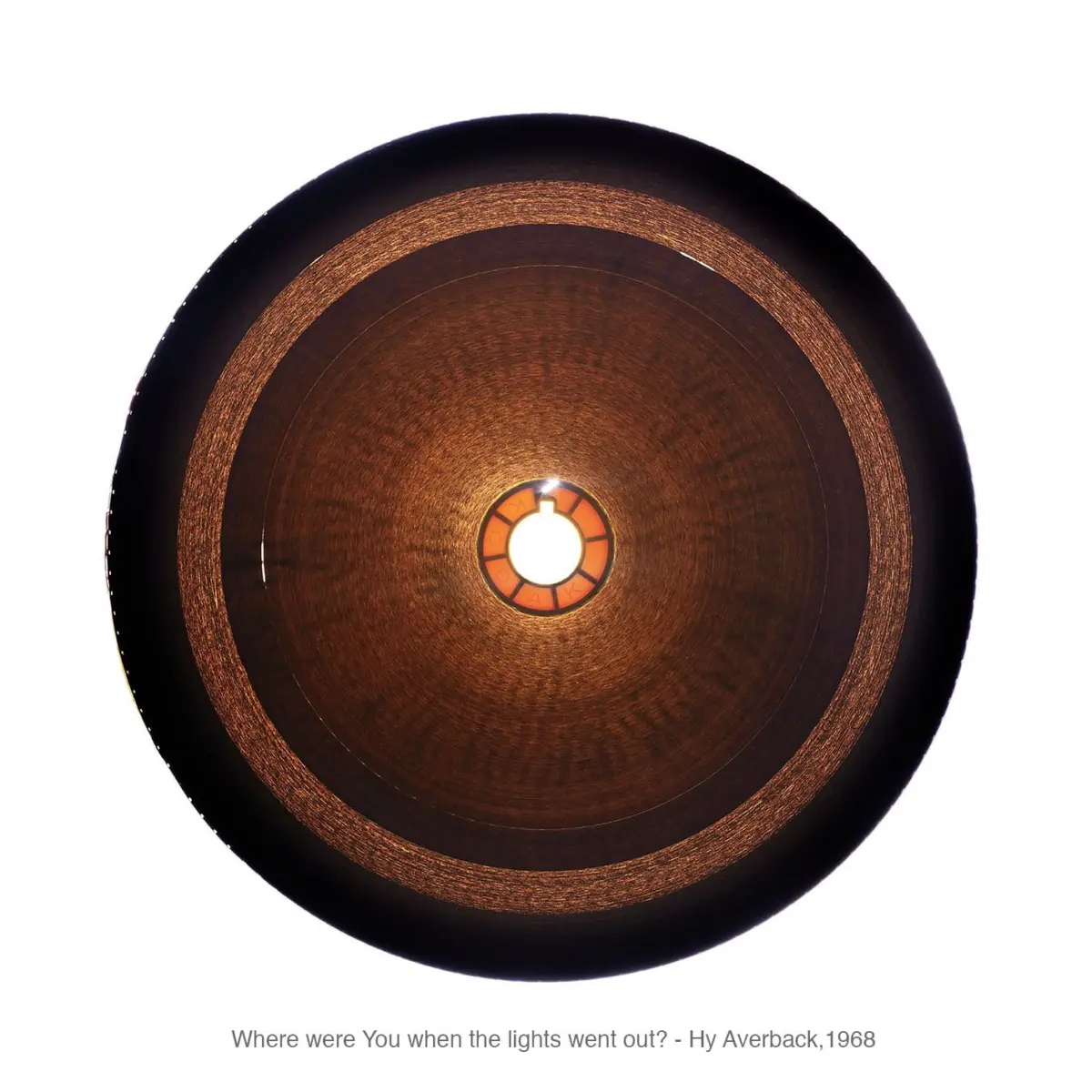 Close-up of a copper-toned circular light fixture with a glowing central bulb and concentric rings.