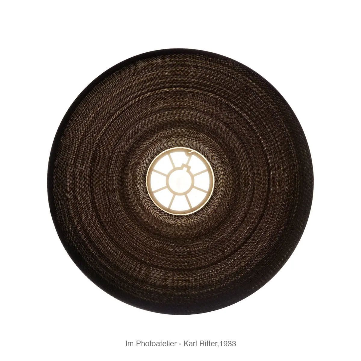 Top-down view of a circular woven straw lampshade with a bright central light