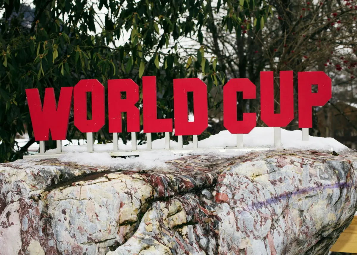 Red letters spelling 'WONDERLAND' mounted on white posts above a snowy rocky ledge, with green foliage in the background.