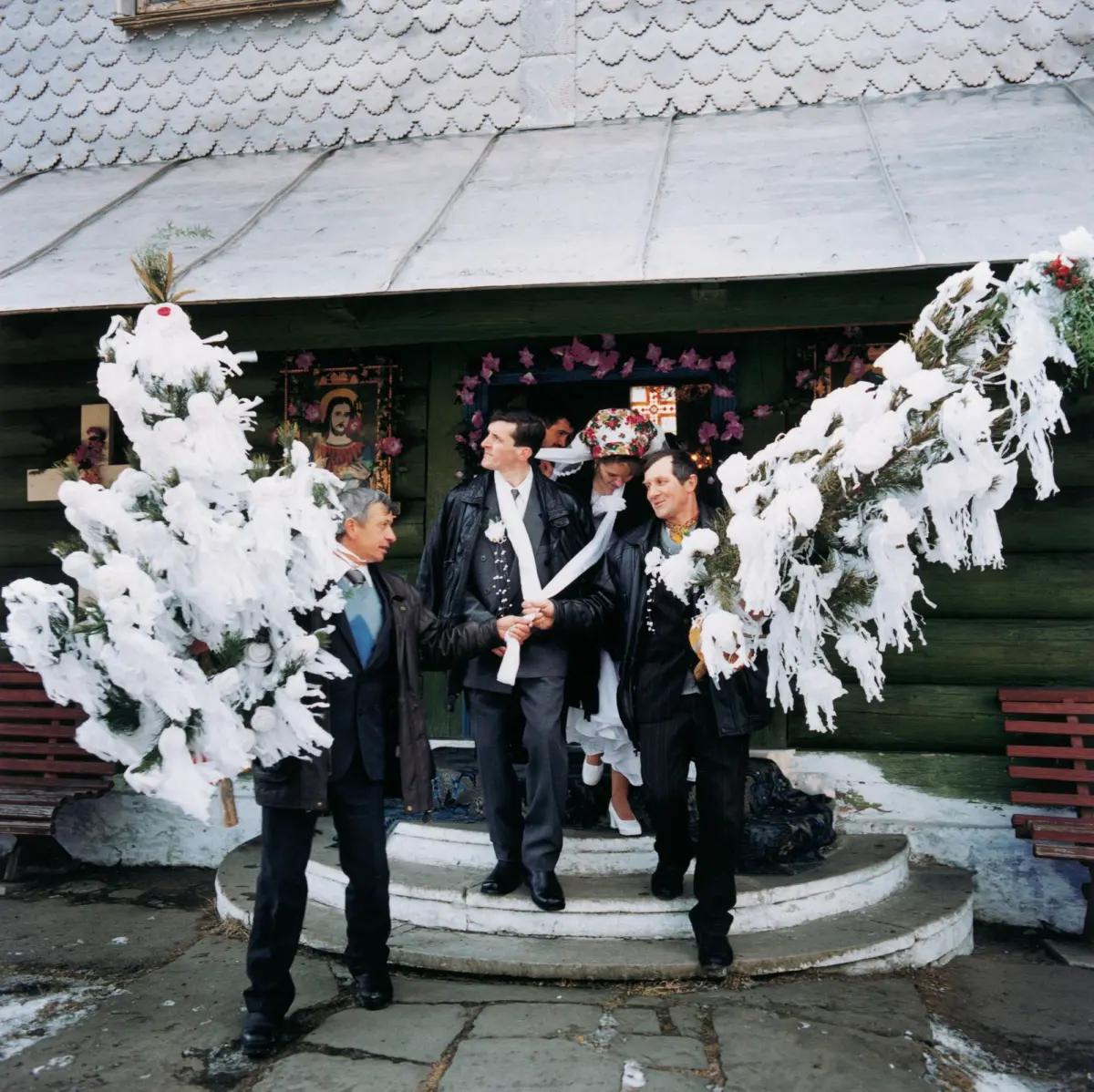 The wedding couple with the "wedding trees" leave the church after the wedding ceremony in the village of Mikulicin