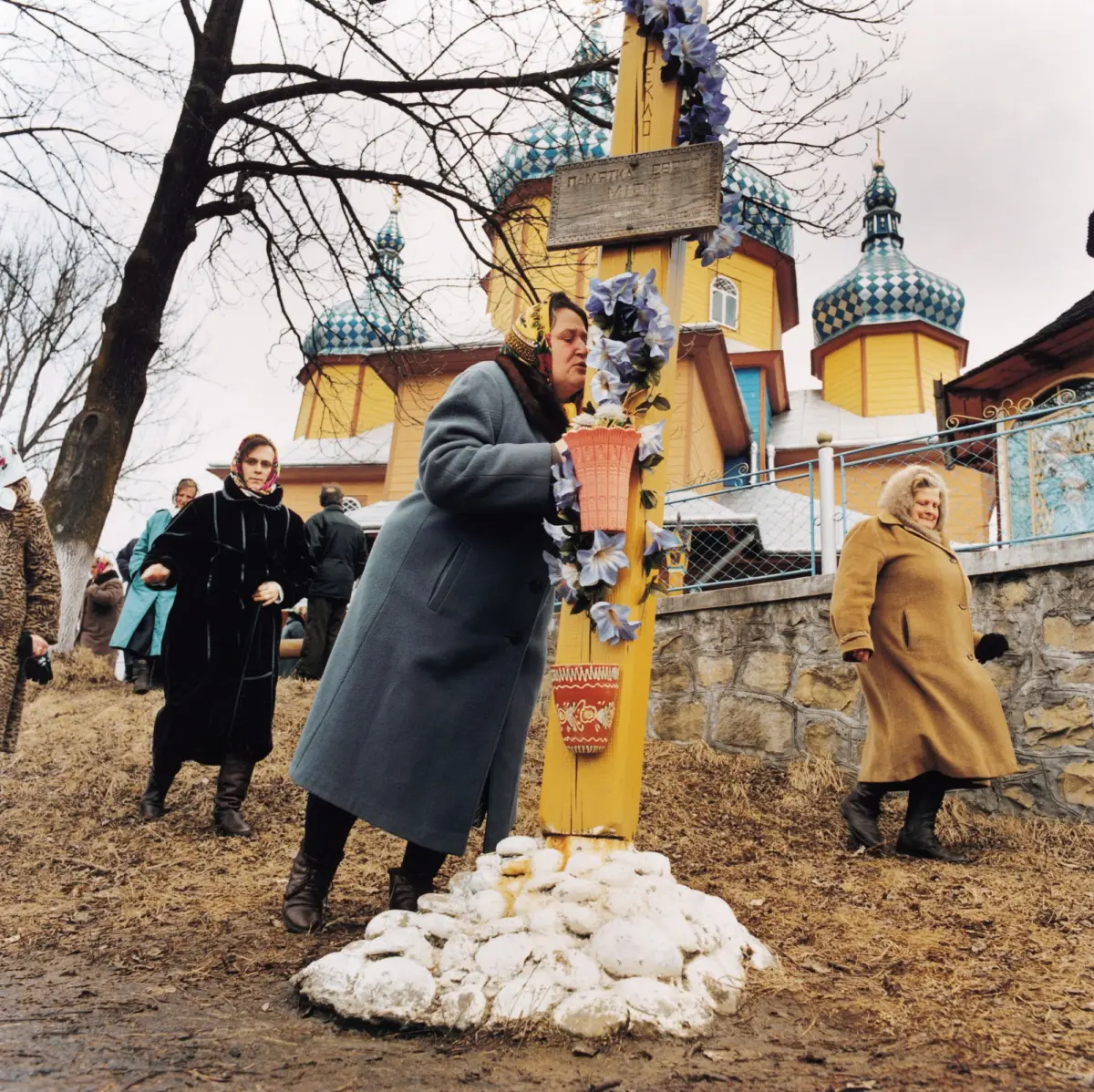 After the ordination of a priest in the village of Vorohda, the faithful kiss a wooden cross in front of the church.