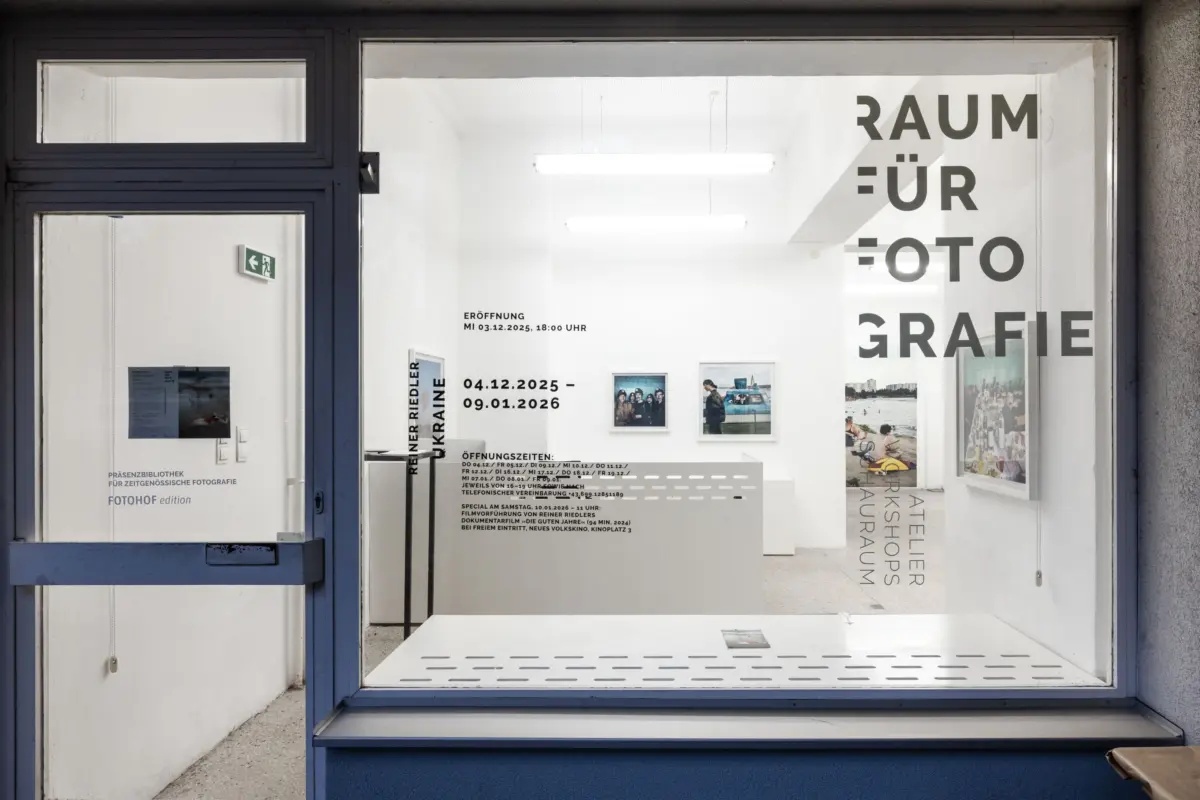 Gallery storefront window displaying bold RAUM FÜR FOTOGRAFIE text, white interior with framed photos.